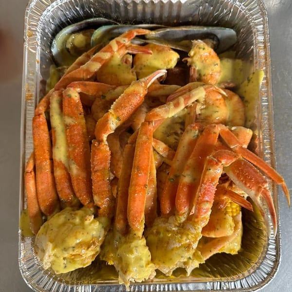 Cajun seafood boil with crab legs, mussels, and corn in a foil container.