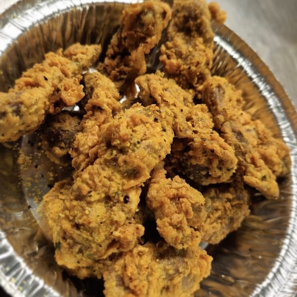 Close-up of golden-brown fried oysters, a Cajun specialty, in a silver foil container.