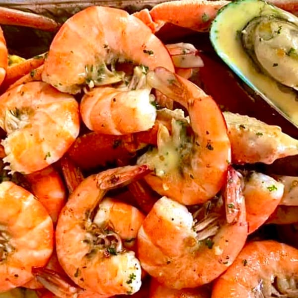 Close-up of Cajun-style shrimp and a green mussel, seasoned with herbs and spices.