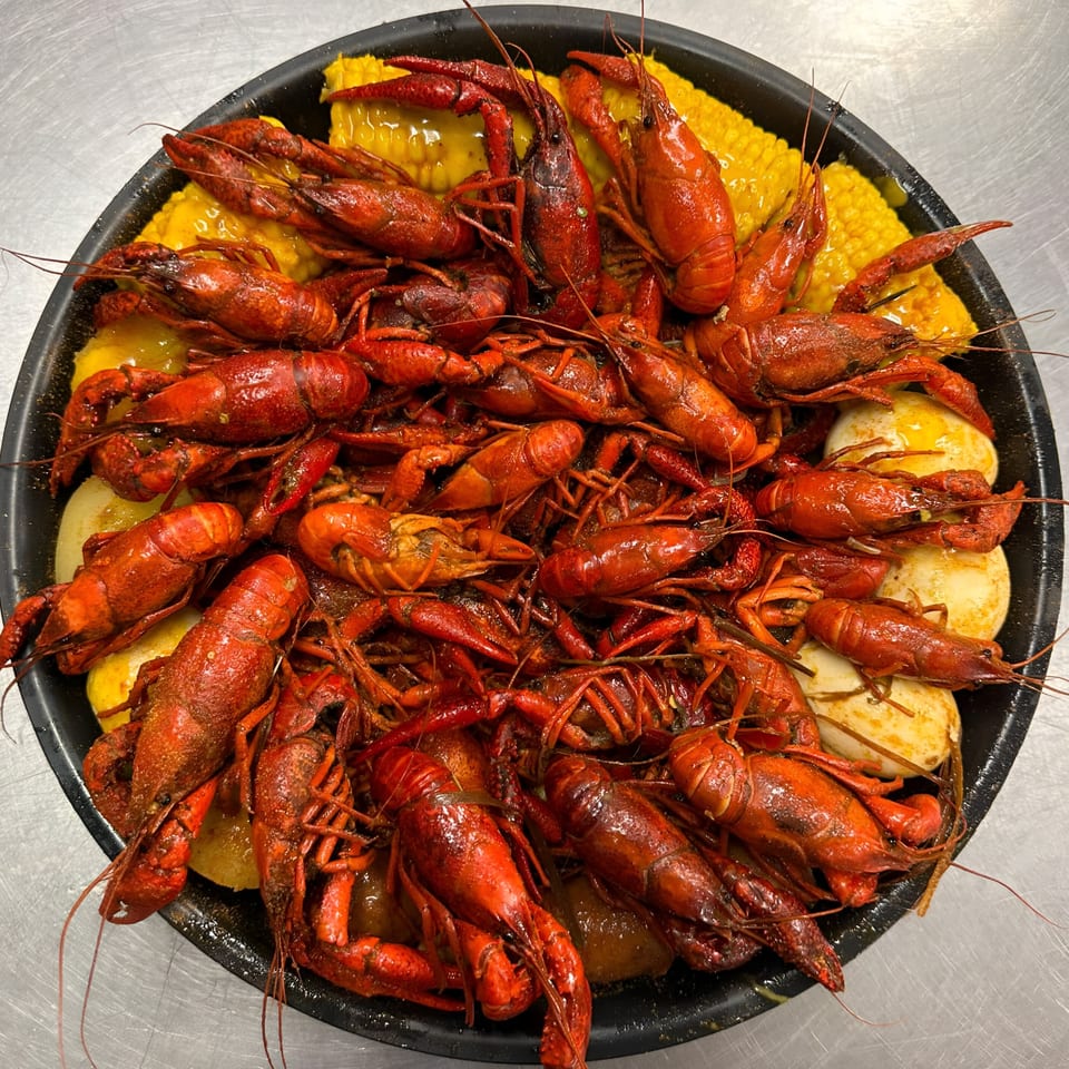 A Taste of New Orleans' Cajun crawfish boil with corn on the cob and potatoes in a black pan.